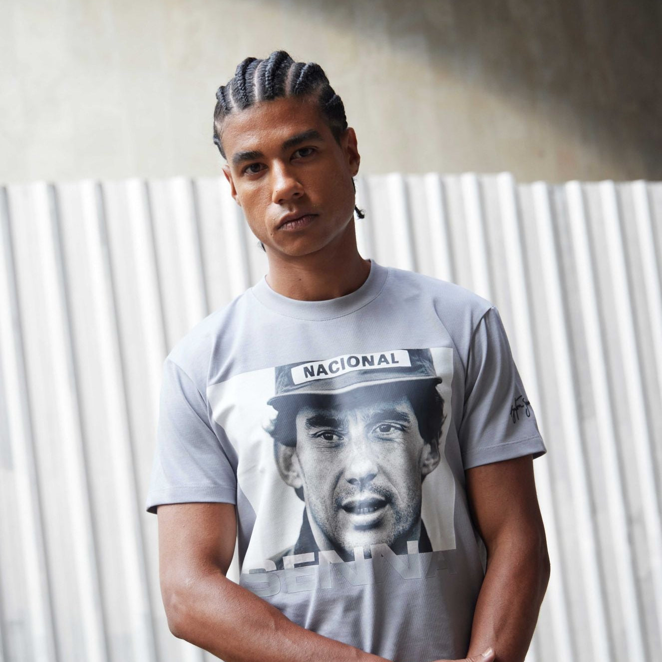 Person wearing a t-shirt with a graphic design of Aryton Senna wearing a cap.