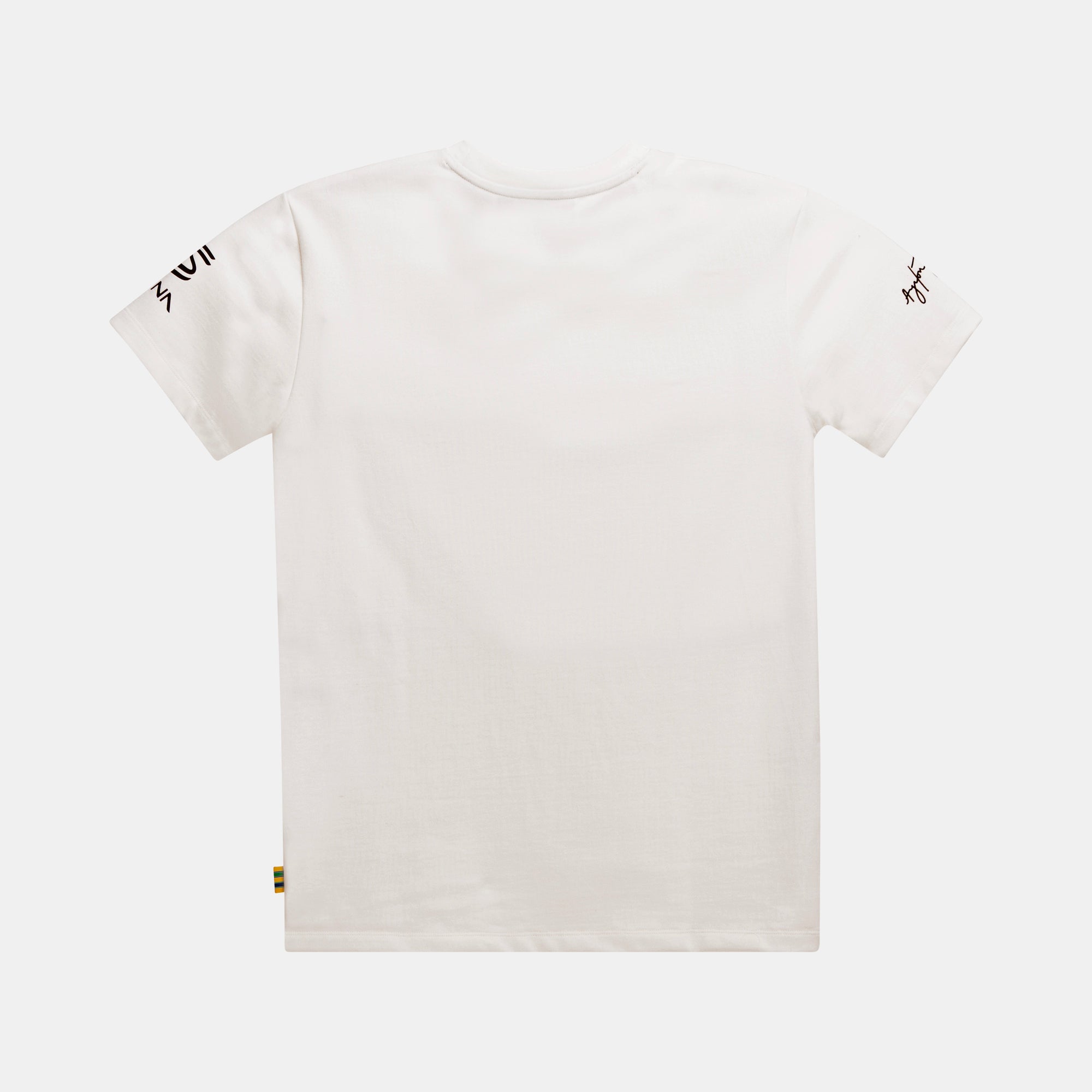 A cream colored short-sleeve t-shirt shown from the back, featuring black signature graphic on the right sleeve, a small black Senna brand on the left sleeve, and a tiny multicolor woven foldover tab near the bottom left hem, set against a light gray background.