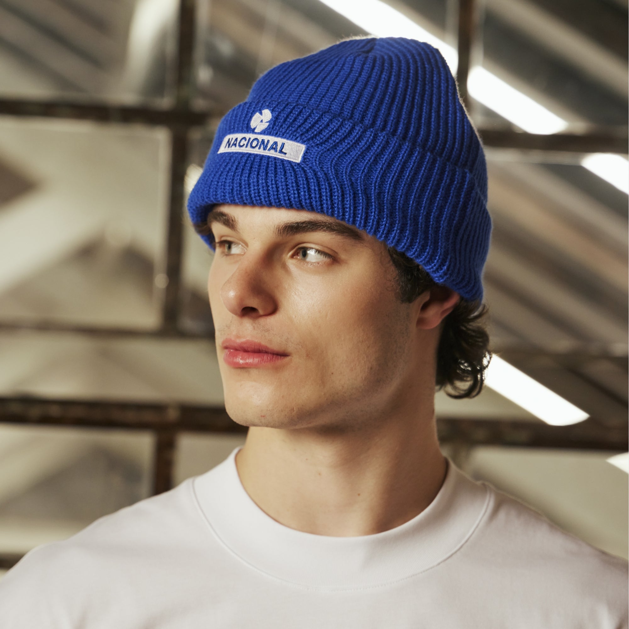 Person wearing a blue beanie with a logo indoors