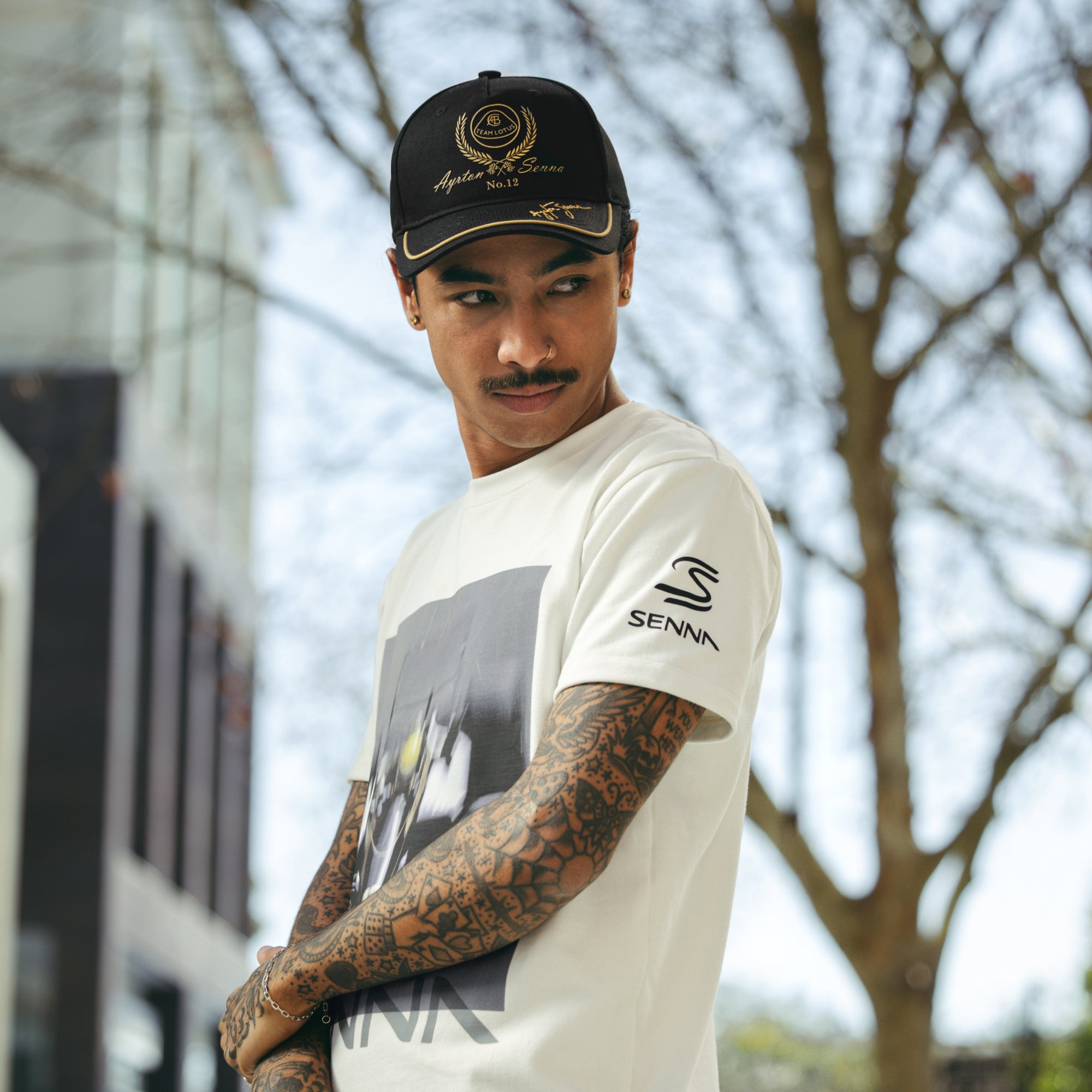 Man wearing cream standard fit t-shirt with Senna branded graphics and logo on sleeve.