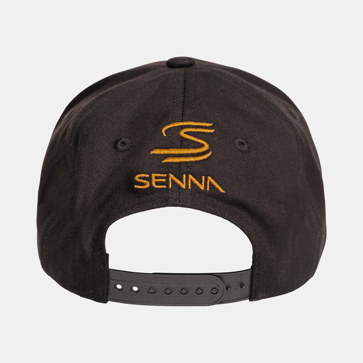 The back of a black Team Lotus and Senna race cap featuring an embroidered gold logo and the word 'SENNA', with an adjustable black strap visible at the bottom, set against a light gray background.