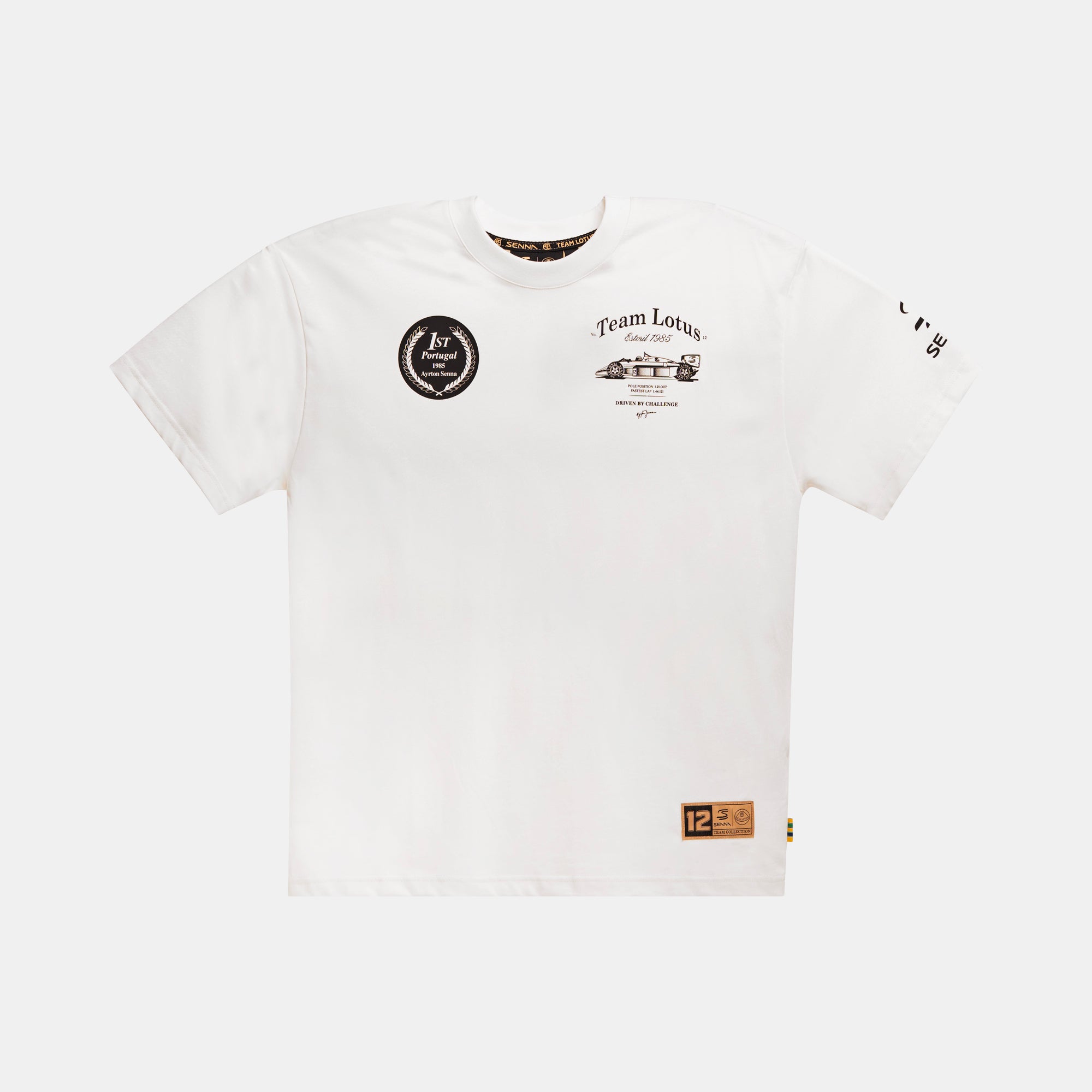A cream short-sleeve crewneck t-shirt featuring a black circular 'Team Lotus' graphic on the left chest, a small vintage race car illustration on the right chest, a black Senna logo graphic on the right sleeve, and a gold leather patch on the lower left hem with '12'.