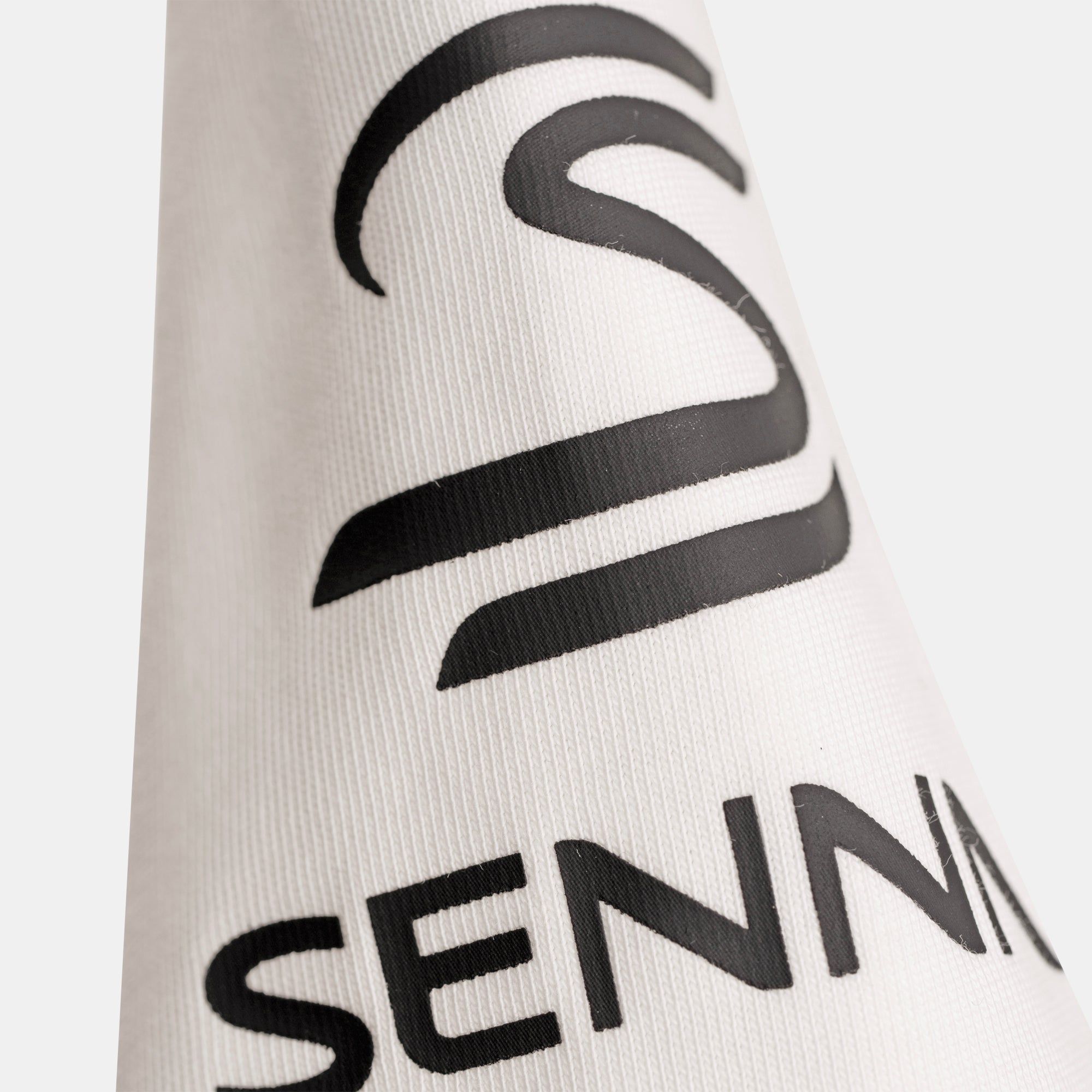 Close-up of a t-shirt sleeve featuring a large black print 'Senna' brand logo.