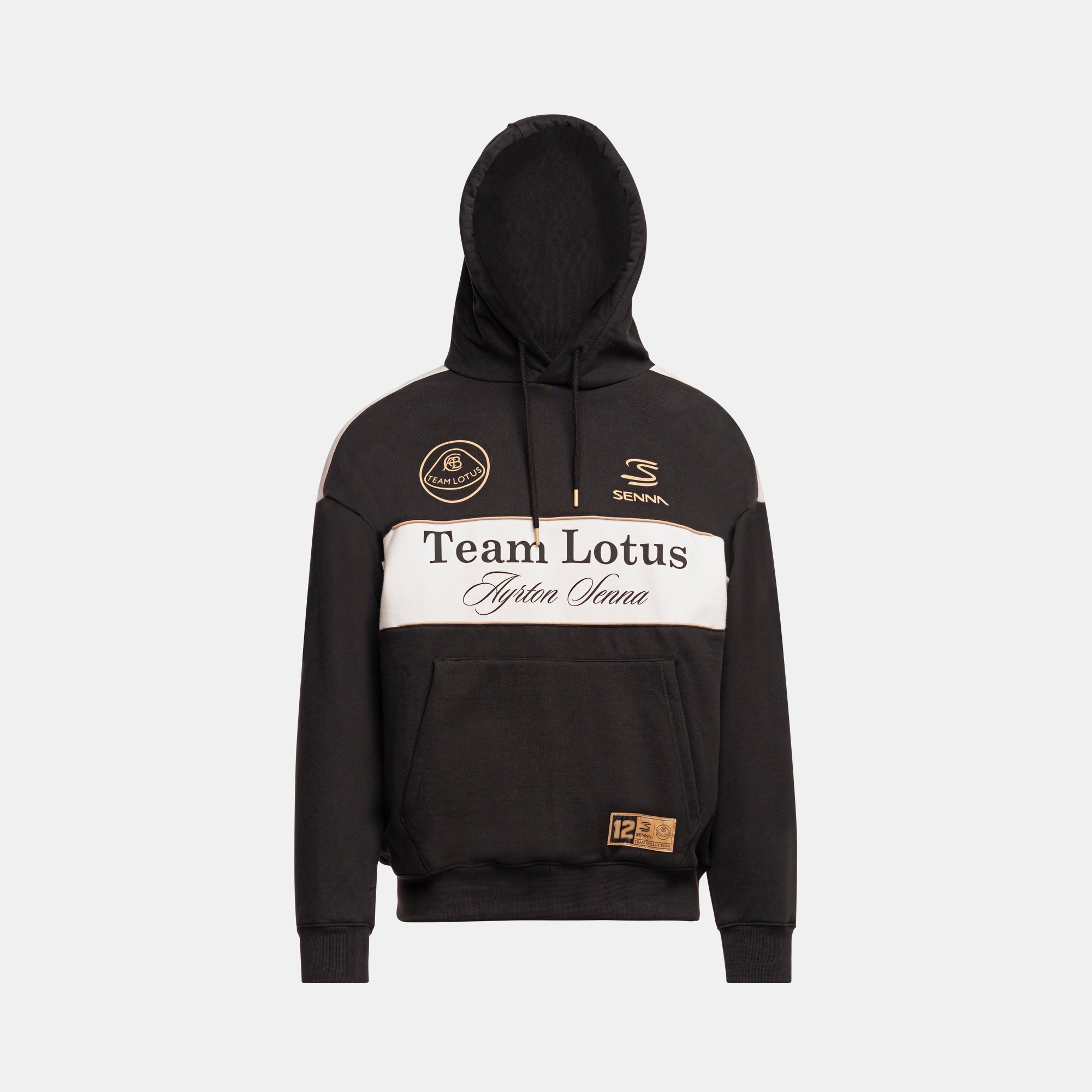A black pullover hoodie with a wide white chest stripe featuring 'Team Lotus' and 'Ayrton Senna' text, plus small Senna and Team Lotus logos on the chest and a small gold patch near the hem, shown on a light gray background.