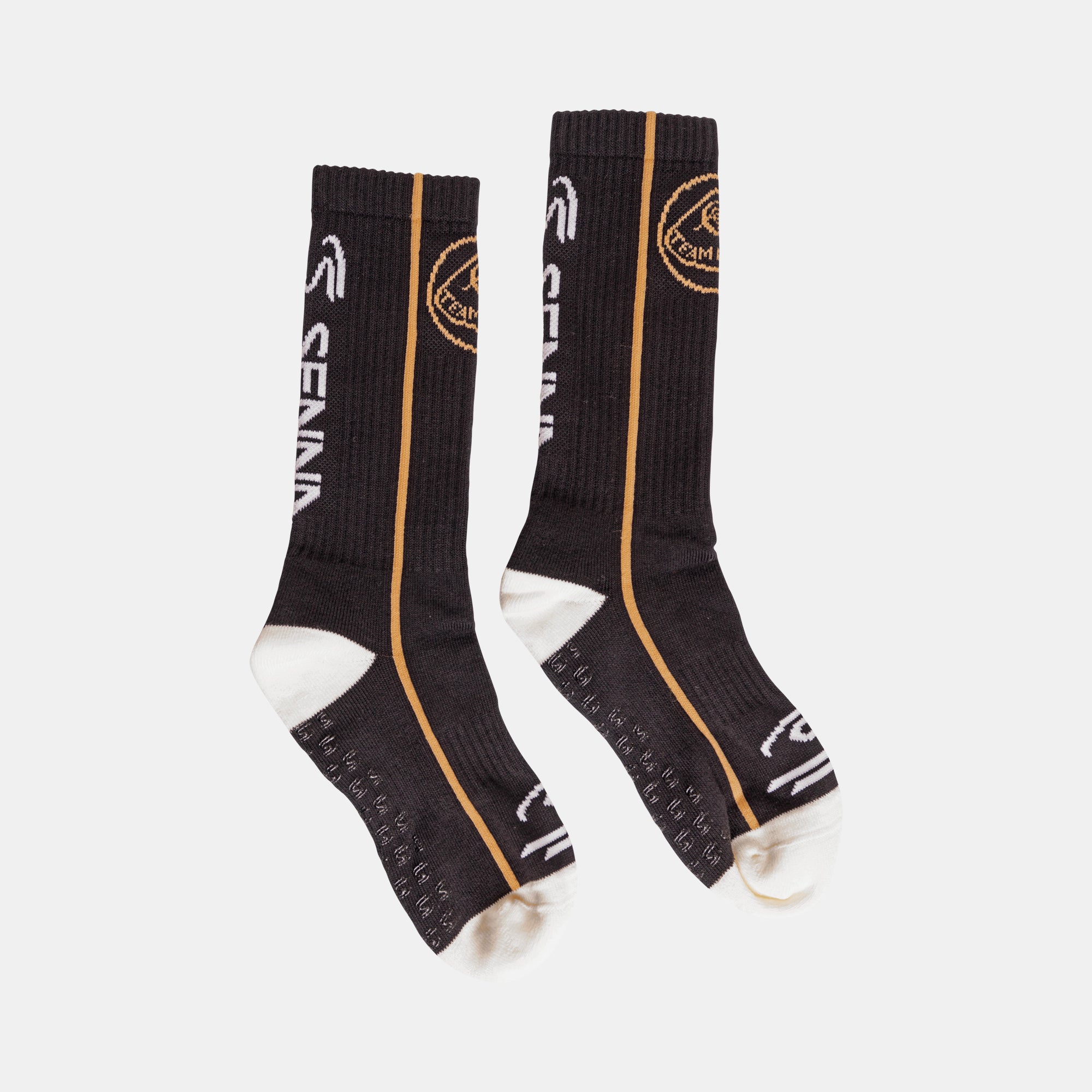 A pair of black crew socks with gold and white Team lotus and Senna branding details, displayed against a light grey background.