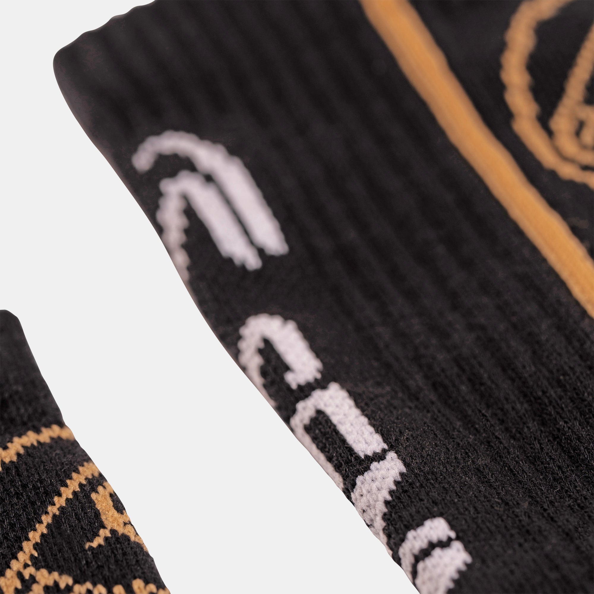 Close-up of a black ribbed sock with white and gold Senna and Team Lotus graphics, shown against a light gray background.