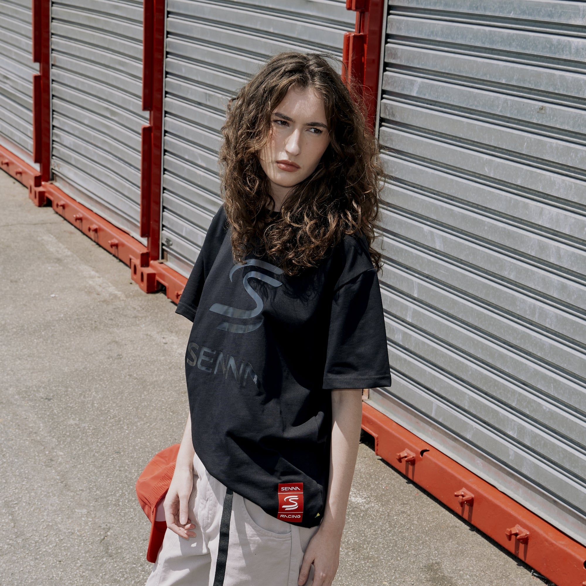 Woman wearing a black  t-shirt with Senna branding in front of metal storage containers