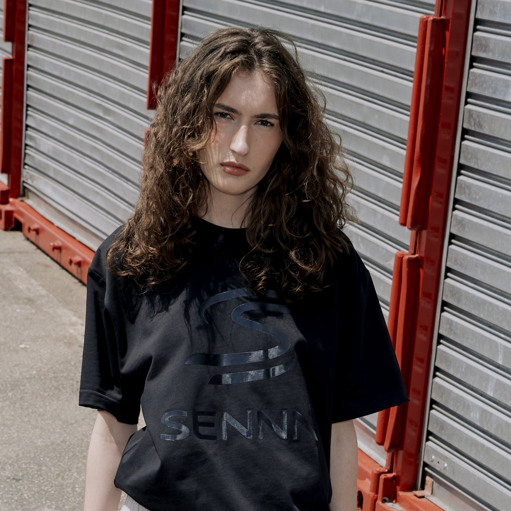 Woman wearing a black Senna relaxed fit t-shirt with branding in front of storage containers